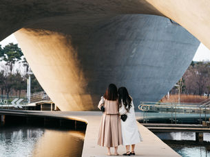 Two women standing beneath a large concrete structure