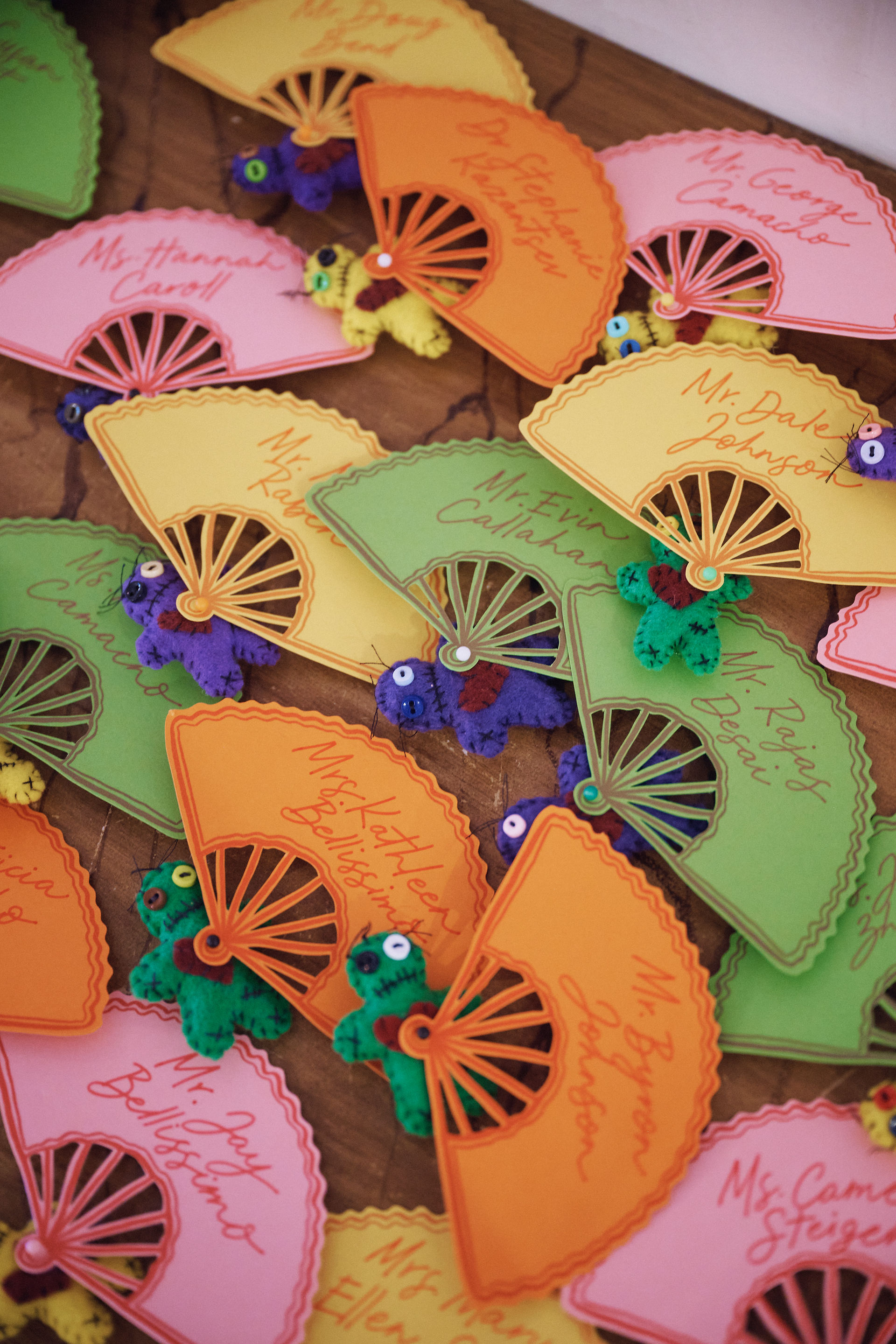 mini paper fans and voodoo dolls as table name cards for a wedding reception seated dinner