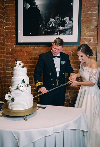 bride and groom cut wedding cake with sword