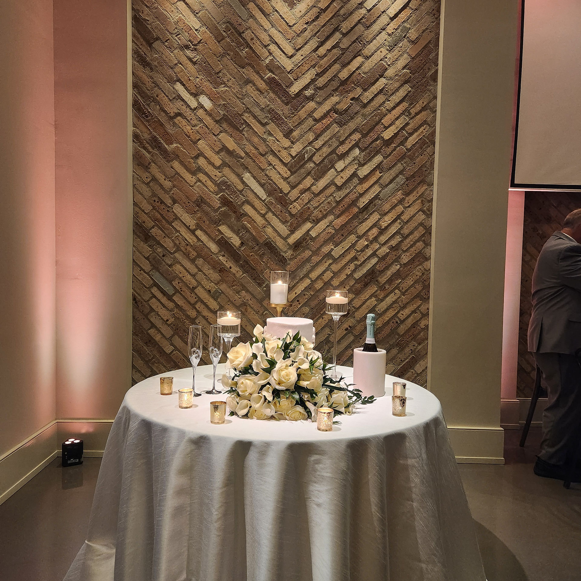 decorative brick wall behind a wedding cake table with cake and flowers