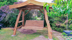 Hollywoodschaukel aus Holz
mit Dach steht im Garten