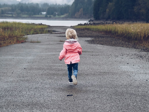 a child in a pink coat running in the rain