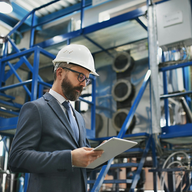 Engineer in hardhat looking at clipboard in industrial facility