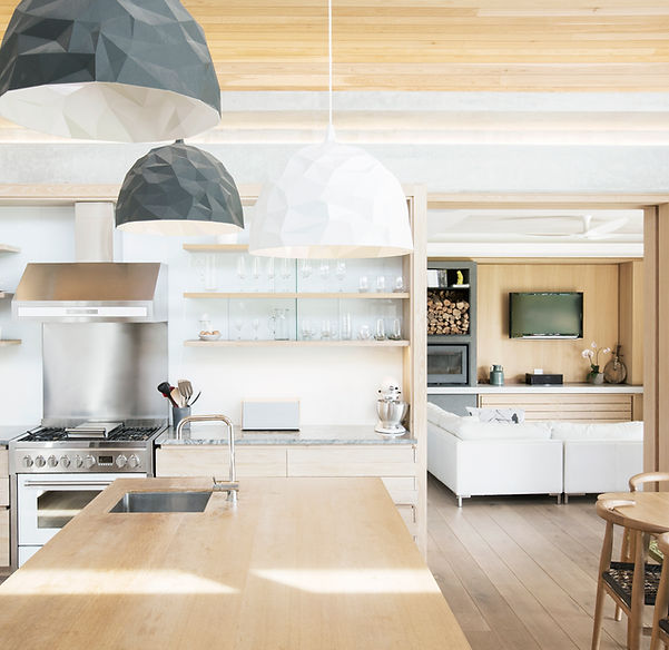 Modern open-concept kitchen and living room with wooden accents, pendant lights, stainless steel appliances, and a cozy seating area in Fayetteville NC.