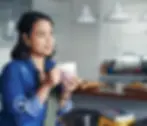 Mujer sosteniendo una taza de café mientras contempla pacificamente