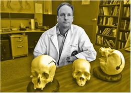 Man in a school office sits behind a desk with skulls