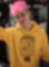 Man with pink hair wearing a yellow hoodie with music notes