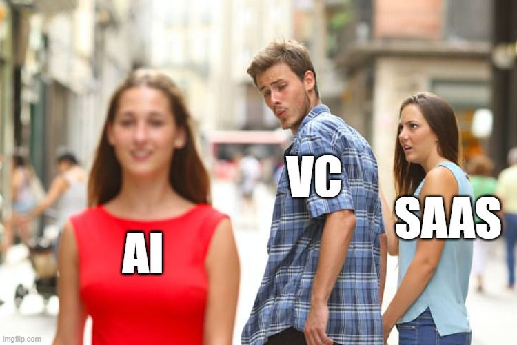 A new take on the distracted boyfriend meme. Man labeled "VC" looks at woman labeled "AI" in red dress, while woman labeled "SAAS" looks annoyed. Urban street scene.