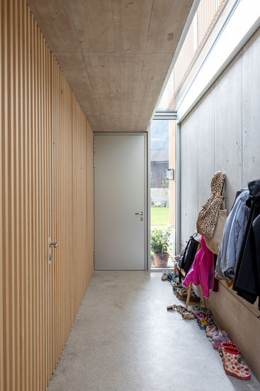 Interioraufnahme: heller Eingangsbereich mit hochwertigen hellen Holz und Sichtbeton sowie Sichtestrich
