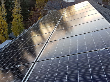 Solar panels installed on a roof, reflecting sunlight in an Edmonton neighborhood.