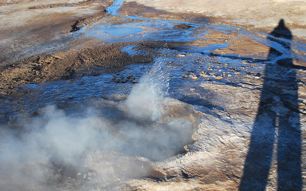 The shadow of a person standing near a bubbling geyser