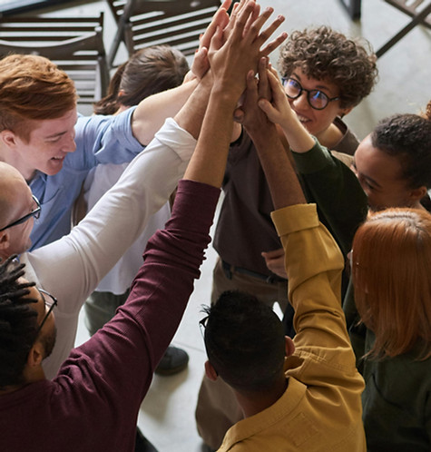 Eight men and women huddled and raising their arms for a group of"high-five"
