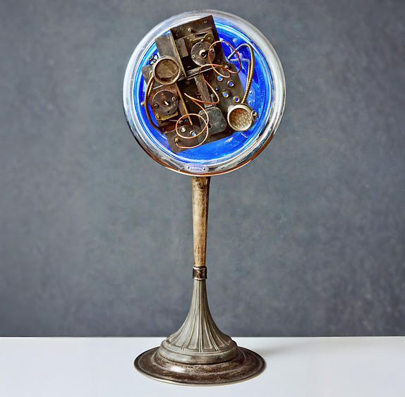 Circular sculpture built into vintage space heater with backlit blue concave surface and embedded metal gears, wires, and lock parts
