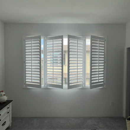 Shades West Hawaii installation of window shutters in bedroom.