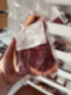 A butchers hand holding a beef ribeye in front of an upright freezer. Dry aged beef