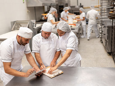 Business manager talking to employees at a food processing plant preparing the production