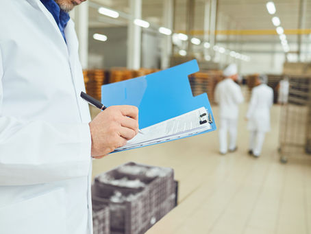 Hands of a person in a white coat make an entry in a folder with papers in a warehouse. Accounting for goods in warehouse.