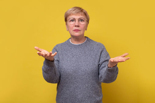 Older woman with glasses with her palms up in the air