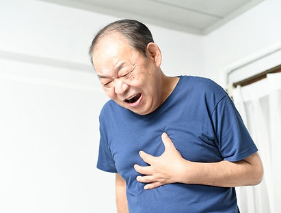 室内で胸部の不調を感じている人物の様子