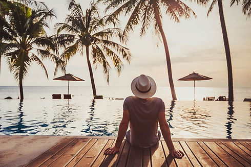 “Man sitting by a tropical pool overlooking the ocean at sunset, Elite Brazil dating lifestyle photo.