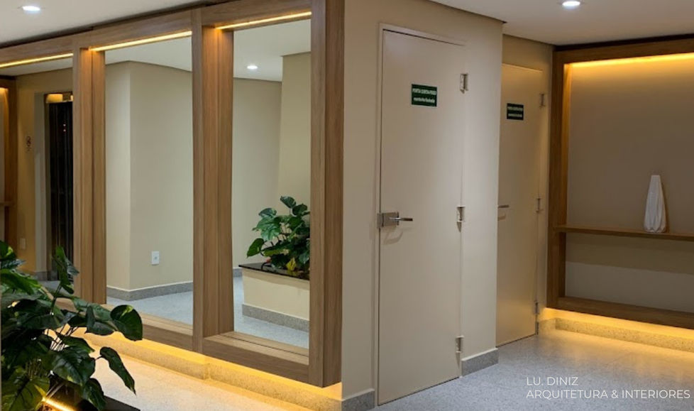 Circulação de condomínio renovada com revestimento amadeirado e iluminação indireta, LU. DINIZ Arquitetura.