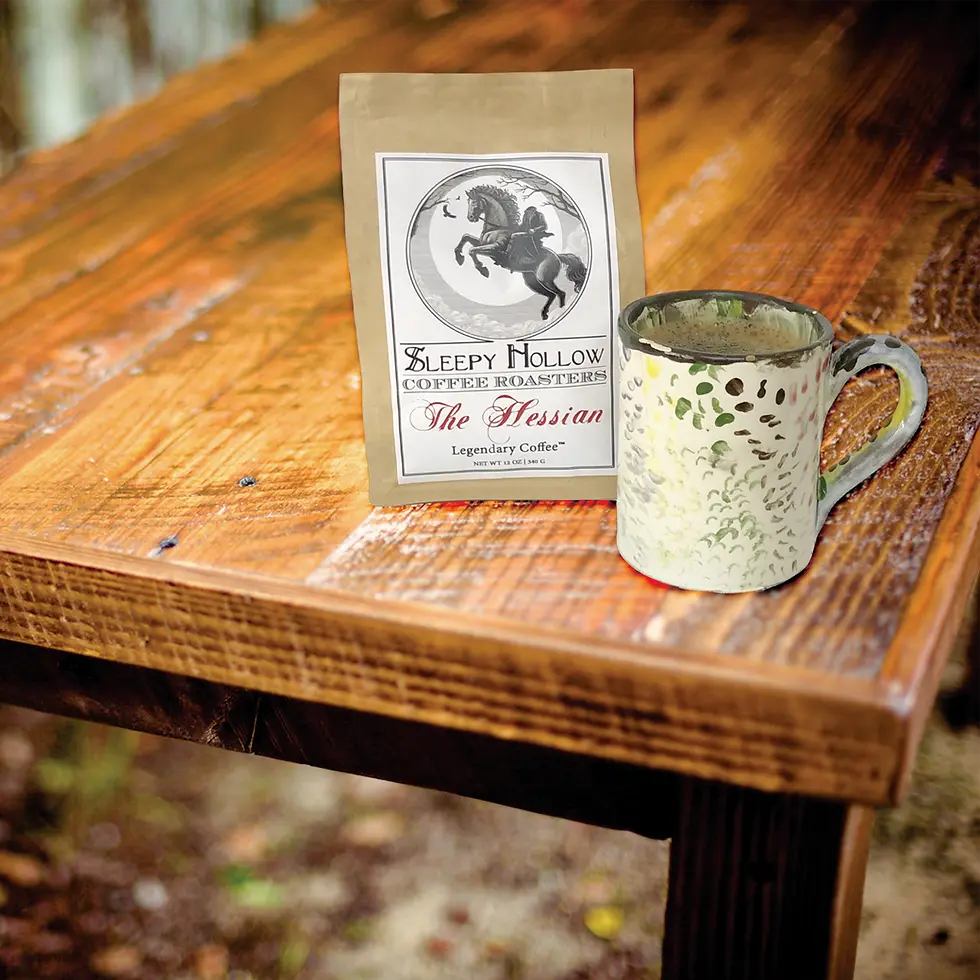 Thumbnail: Lifestyle Image of coffee bag The Hessian from Sleepy Hollow Coffee Roasters with arts and crafts mug on a rustic wood table