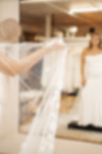 Bride holding a sheer veil while viewing herself in a mirror.