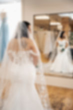 Bride standing in front of a mirror looking at her reflection in a gown