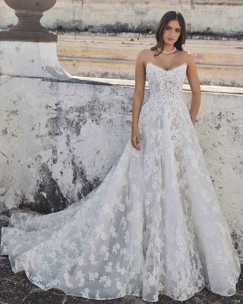 Elegant woman in a strapless WEDDING DRESSES, stands on outdoor stairs.