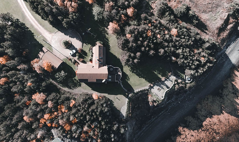 Overhead aerial drone photograph of a rural acreage showing the house, outbuildings, driveway approach and treed property lines — the site-overview shot that helps Grande Prairie and Peace Country acreage listings sell faster