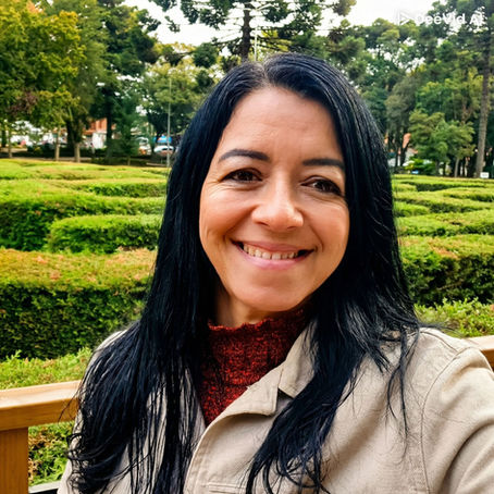 mulher sorrindo cabelos longos preto numa praça ao ar livre