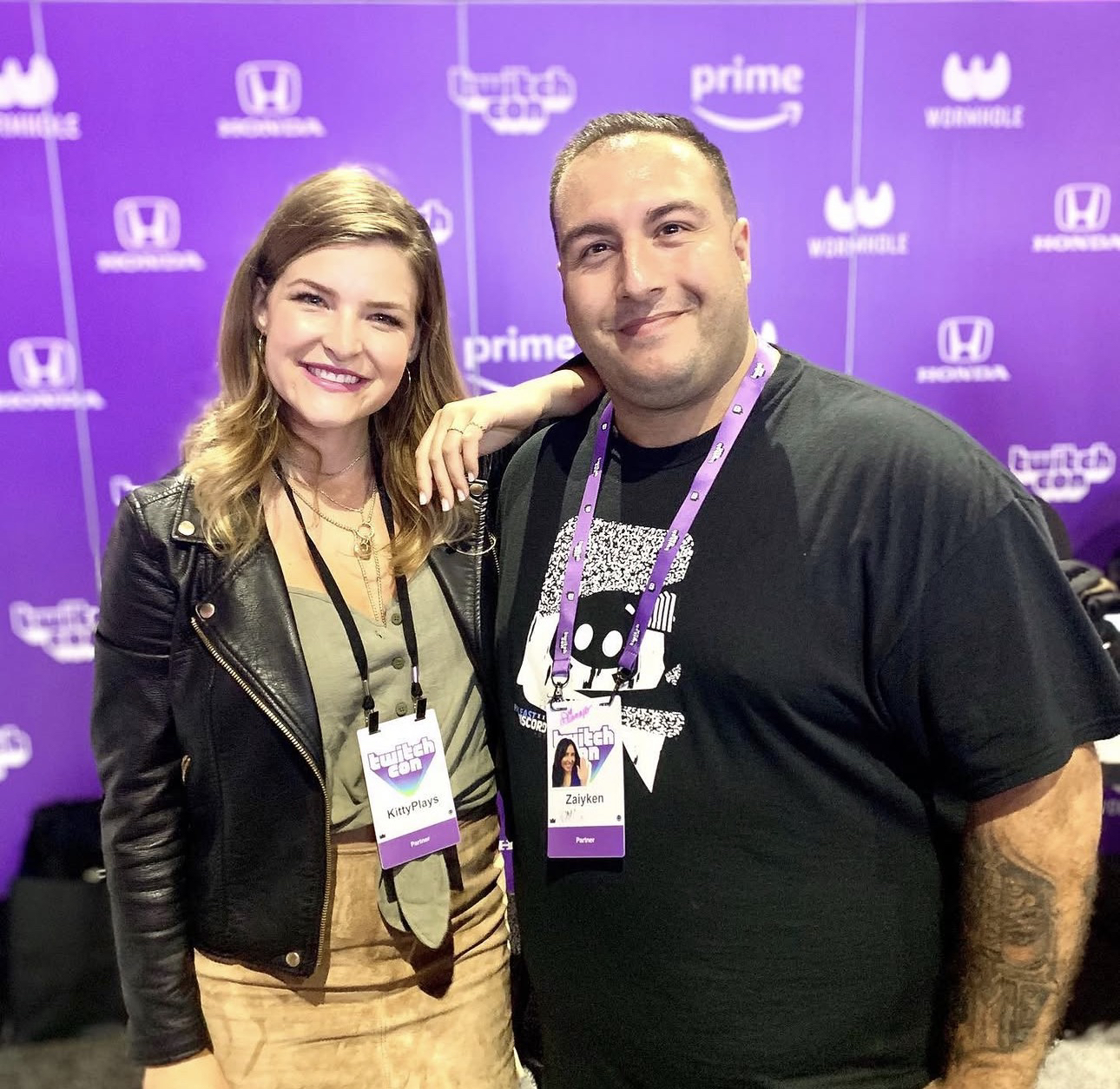 Zaiyken junto a otra asistente frente al fondo morado de TwitchCon