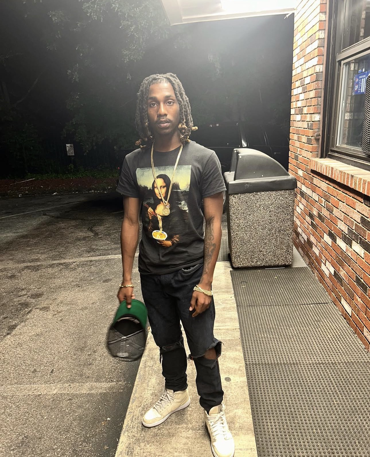 KDOT LMG de pie de noche, con una gorra en la mano