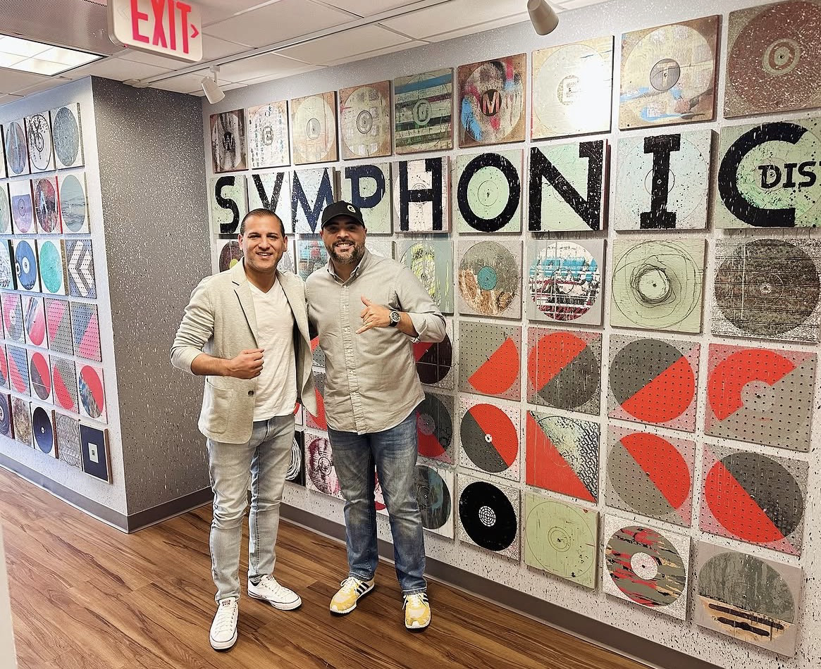 Domenic Marte junto a otra persona, frente a una pared decorada con discos