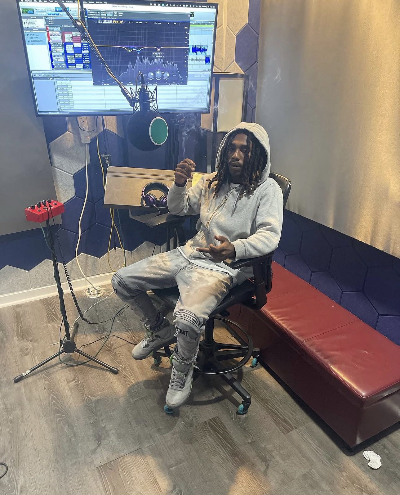 KDOT LMG sentado en un estudio de grabación, con una pantalla de edición de audio detrás