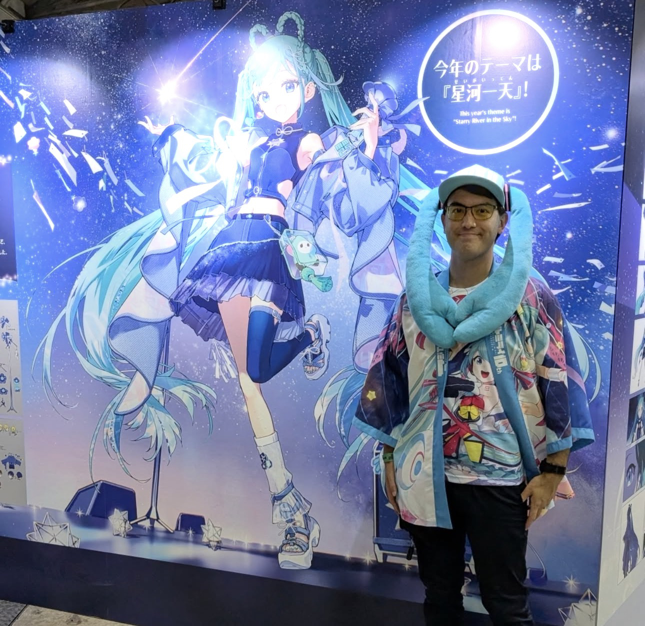CaptainBryan con una gorra celeste, frente a un póster de Hatsune Miku