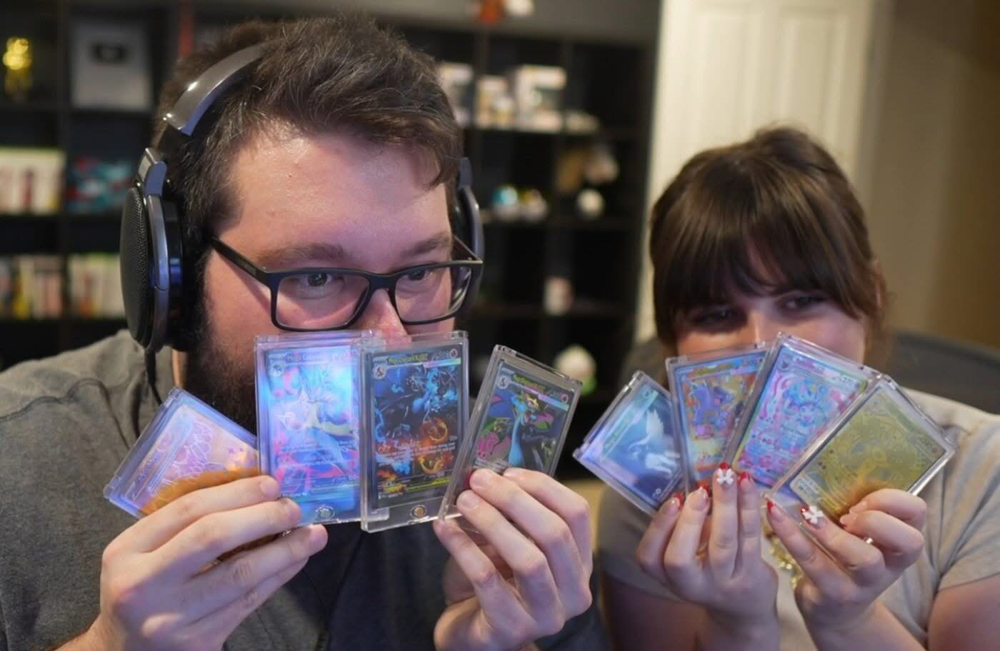 Flats y su esposa sosteniendo cartas de Pokémon frente a sus rostros