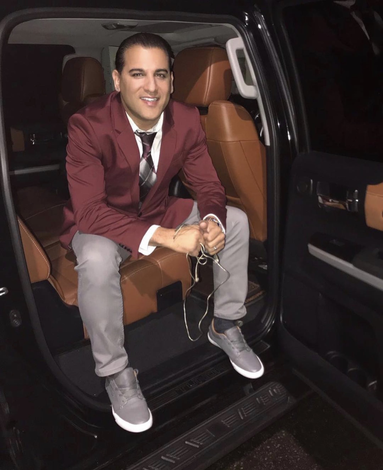 Domenic Marte sentado en la puerta abierta de una camioneta, de noche