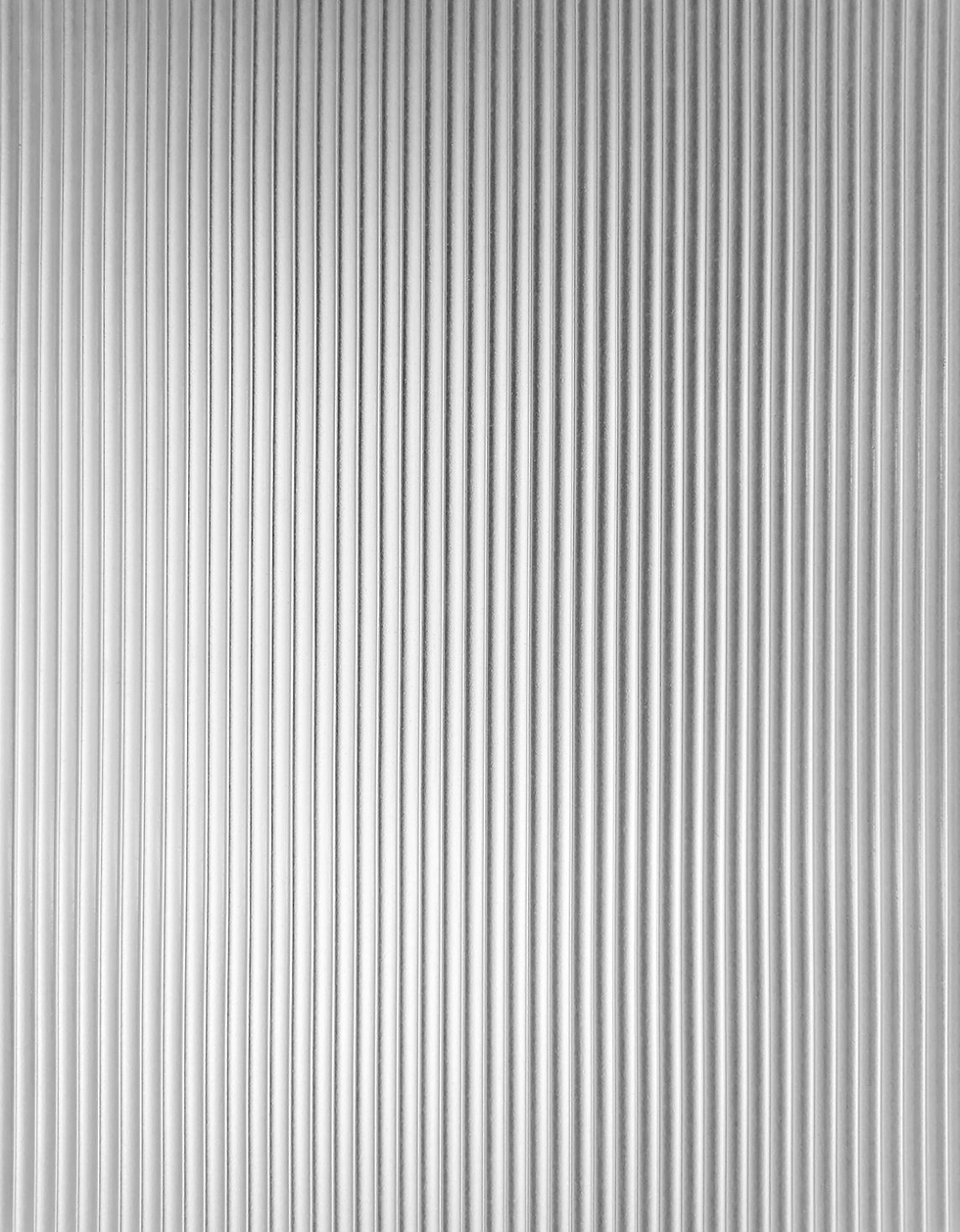 Close-up of a silver corrugated metal wall with vertical ridges, creating a simple industrial pattern.