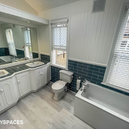 Dual sink Victorian style bathroom with blue metro tiles on walls and white painted wood panelled walls