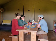 Group playing board games at Top of the Woods eco-luxury camping and glamping site in Pembrokeshire. Settle in together after a day of exploring, switch off from screens and enjoy relaxed evening fun in the Welsh countryside.