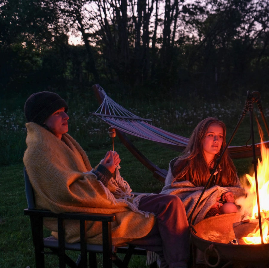 Your best friends and family gathered around a campfire outside the Safari Lodge at Top of the Woods, Pembrokeshire, Wales – a luxury eco glamping holiday retreat perfect for relaxed, nature-based slow-travel stays.