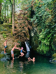 Secret waterfall and wild swimming near Top of the Woods, Pembrokeshire. Family woodland walk leading to a hidden waterfall for paddling and outdoor adventure.