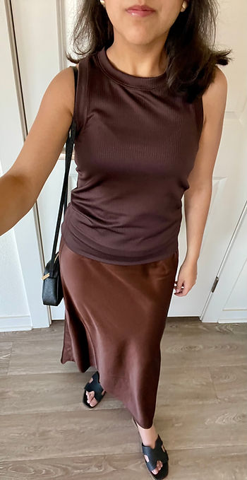 Brown tank top, round gold earrings, brown satin skirt, black crossbody bag, black sandals