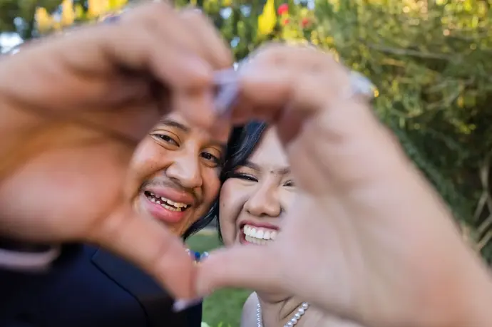 wedding couple making a heart shape with their hands to frame their smiling faces in Lancaster