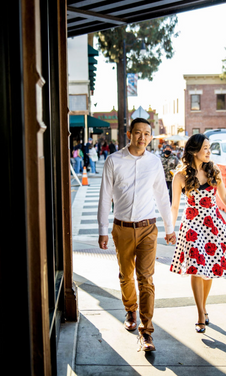 Engagement photo of couple walking on a sunny downtown street