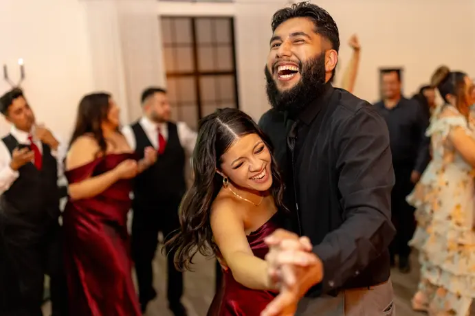 a bridesmaid dances with a guest and they laugh