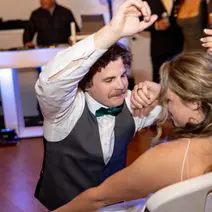 Man in vest kneels to woman, dancing at party