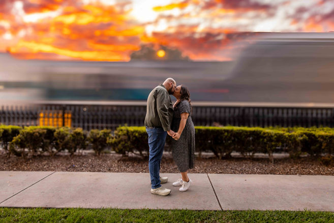 couple standing with each other as a train passes. slow shutter used to blur the train at sunset couples photography photographer tom keene Old Towne Orange