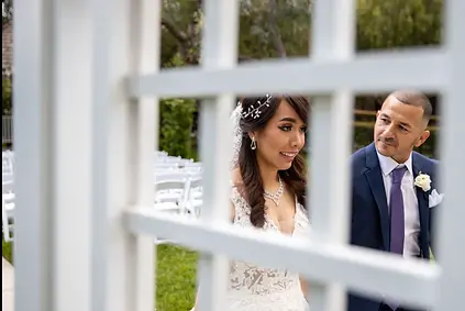 Bride and groom seen through a white lattice fence